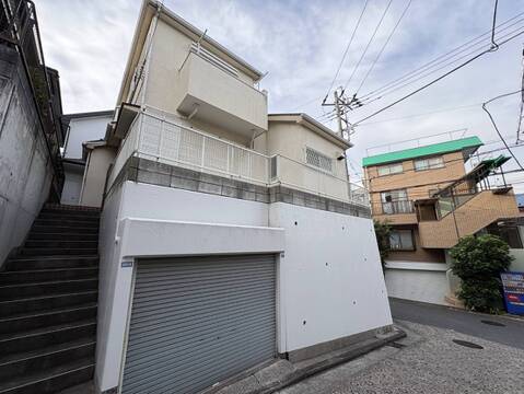 白い外壁の建物とシャッター付き車庫