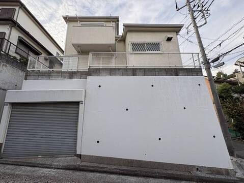 白い外壁の戸建て外観とシャッター付き車庫