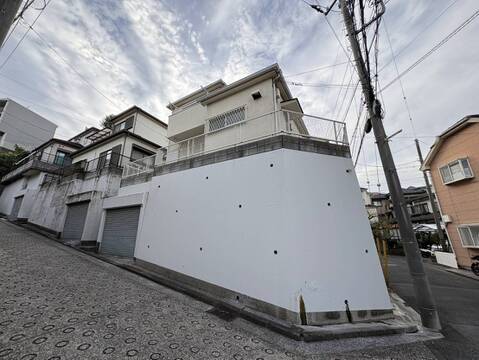 坂道沿いにある白壁の住宅外観