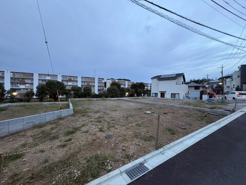 道路沿いの更地と周辺の住宅街