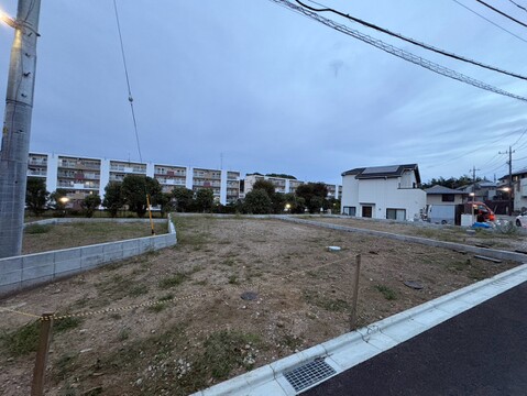 道路沿いの更地と周辺の住宅