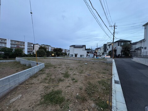 道路沿いの更地と周辺の住宅街