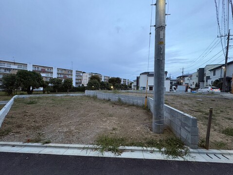 道路沿いの更地周囲に住宅や電柱が見える