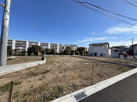 道路沿いの整地された更地周辺に住宅あり