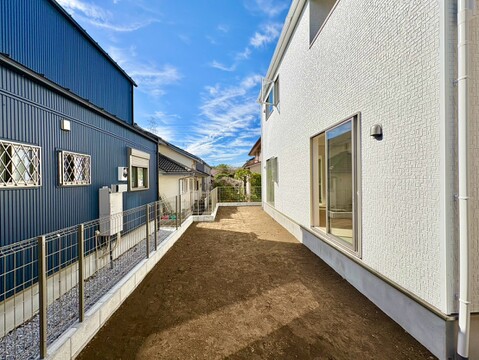 建物脇の砂利敷き通路とフェンス