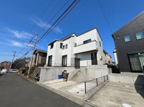 白い外壁の戸建て住宅と前面道路