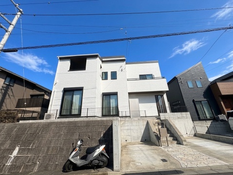 白い外壁の住宅とコンクリート舗装の外構
