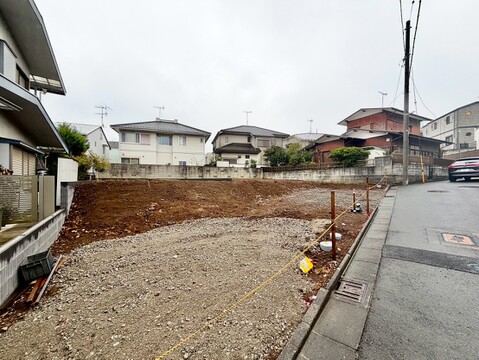 道路沿いの整地された敷地と周辺住宅