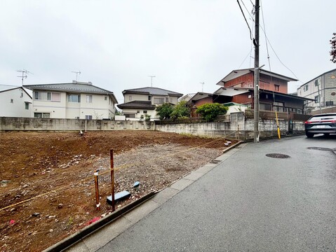 前面道路と隣接する更地、周辺に住宅が見える
