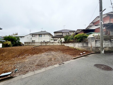 道路に面した更地と周辺の住宅