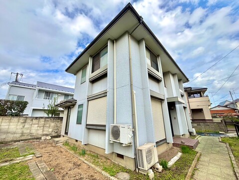 白い外壁の戸建て住宅と敷地内の植栽