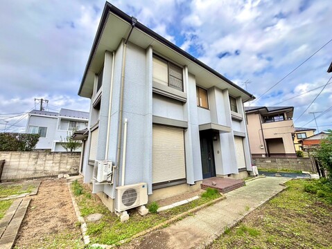 2階建て住宅の外観敷地内に空調室外機と植栽あり