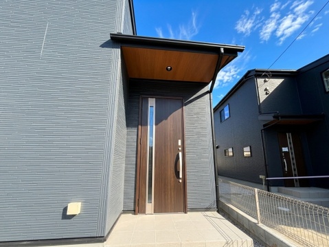 木目調の玄関扉と外壁が見える住宅の玄関