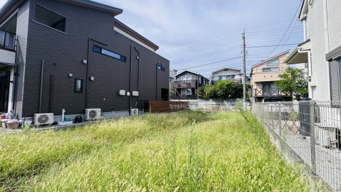 住宅に囲まれた草の多い敷地の外観です