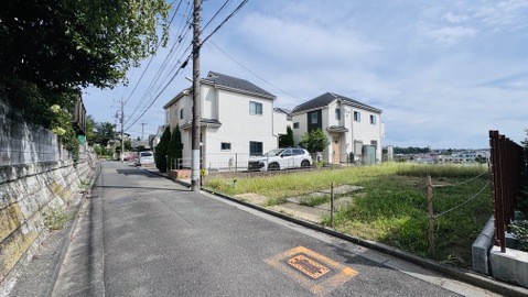 住宅街の角地にある空き地と隣接する住宅の外観です