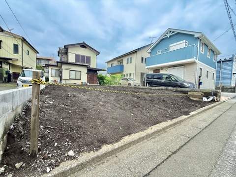 道路に面した住宅の外観と整地された敷地