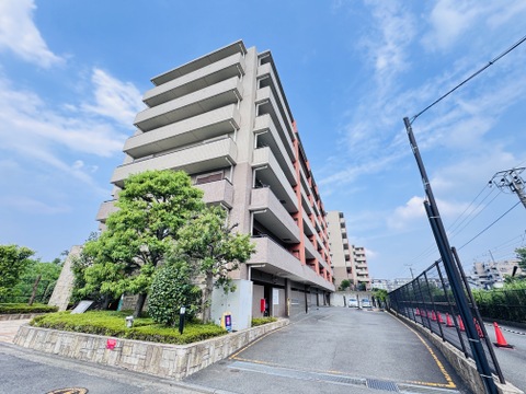 緑に囲まれた多階建てマンションの外観です