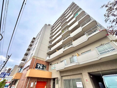 周辺の建物と共に写るマンションの外観写真