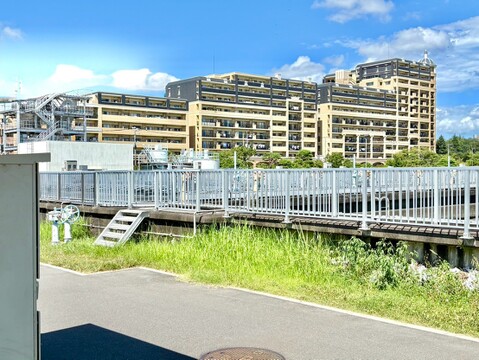 高層住宅の外観と周辺の緑地が見える景観です