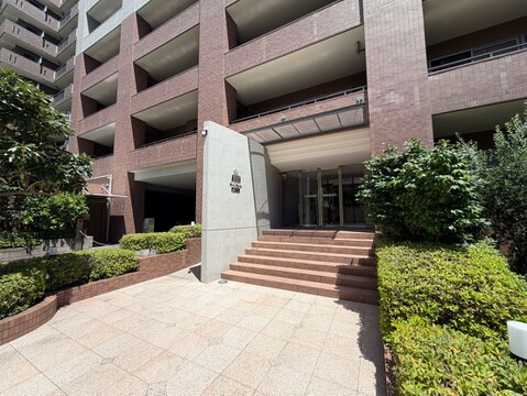 マンションのエントランスと周囲の植栽が見える外観