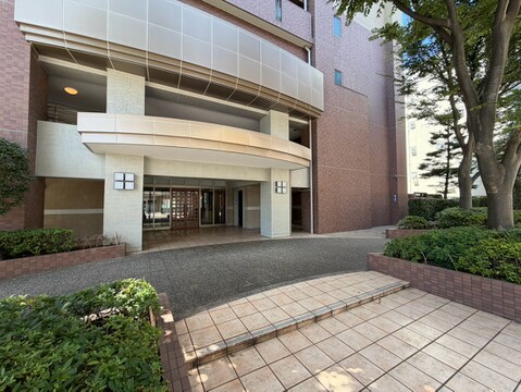 建物外観とエントランス付近の植栽が見える敷地前面