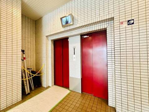 タイル張りの壁と赤い扉のエレベーター風景です