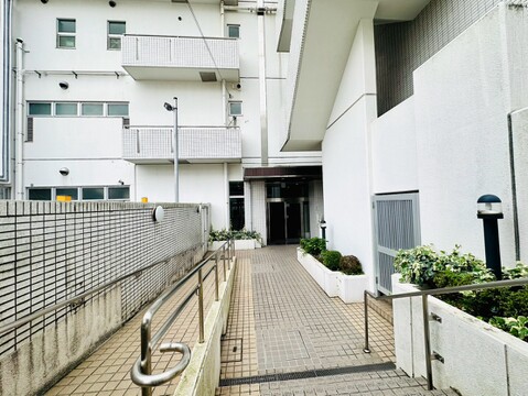 建物外観と通路、集合住宅の一部が見える様子です