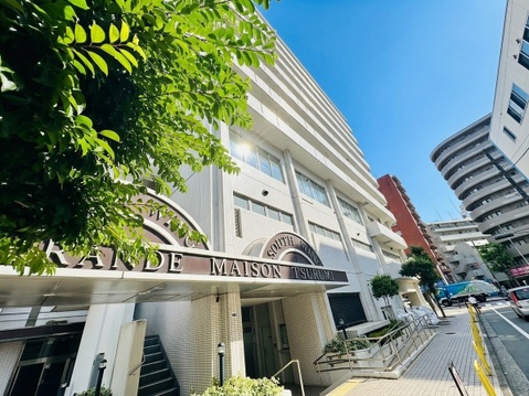 複数階建てのマンション外観と周辺の街並みが見えます