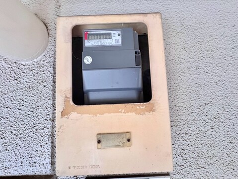 建物のエントランスと周囲の緑地が見える外観写真です