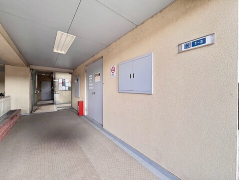 マンションの共用廊下と掲示板が見える通路