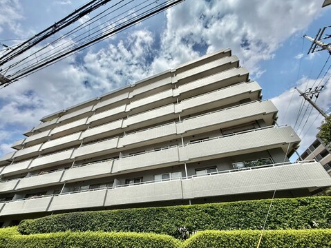 青空を背景にした多階建てのマンション外観です