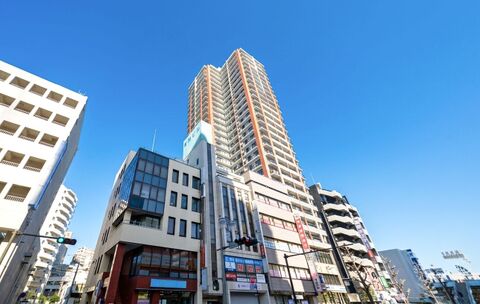高層ビルと周囲の中低層建物が並ぶ街並みの外観写真です