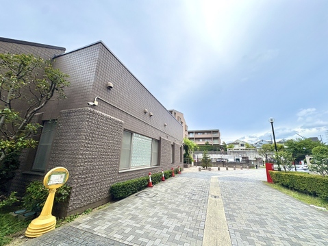 建物の外観と敷地入口の歩道が見える風景です