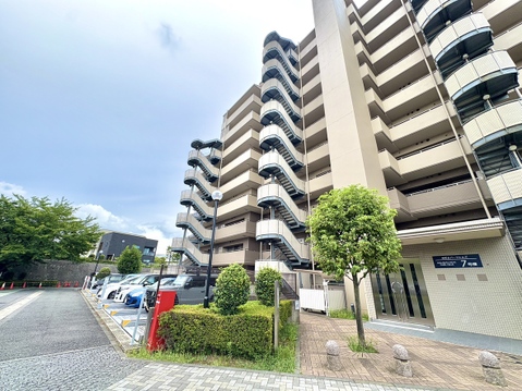 複数階建てのマンション外観と周辺の植栽が見える風景