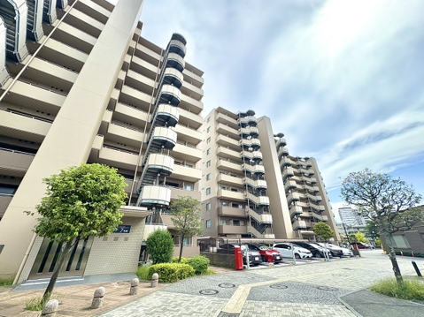 マンションの外観と駐車場の様子が見える風景