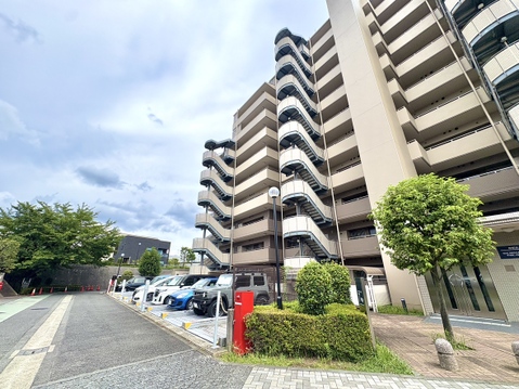 複数階のマンション外観と敷地内の駐車場が見える風景