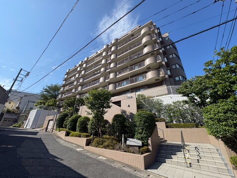 多階建てのマンション外観、周囲には緑がある街並み