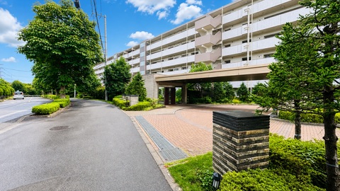 緑豊かな敷地内のマンション外観と入口付近の歩道