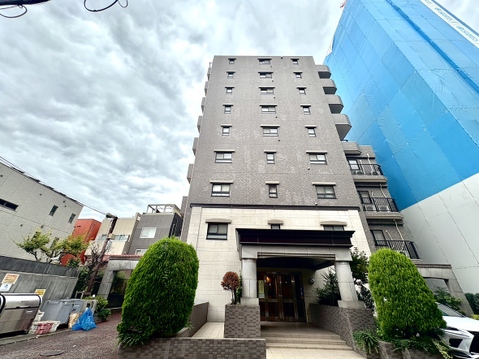 複数階のマンション外観、周囲に建物と緑がある