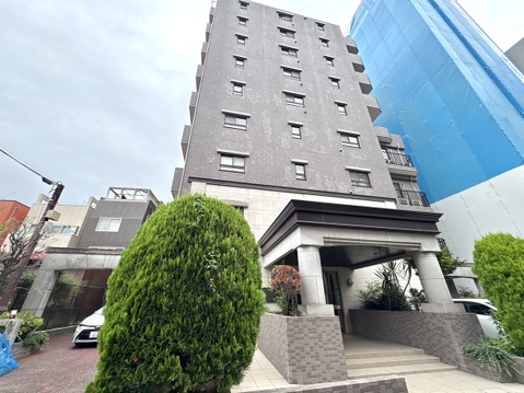 高層のマンション外観、植栽があるエントランス付近