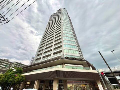 高層のマンション外観周囲に建物が立ち並ぶ都市環境