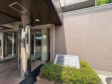 建物のエントランスと周囲の植栽が映っています
