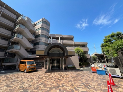 複数階建てのマンション外観と広めのエントランス付近の様子
