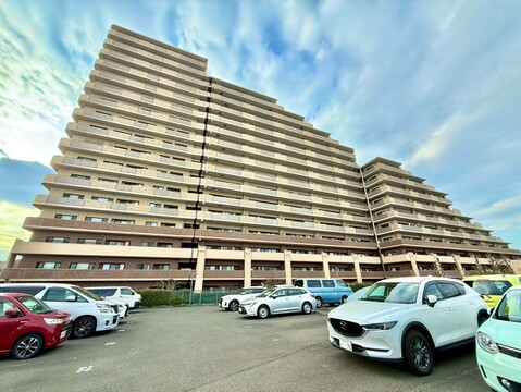 複数階の大規模マンションと駐車場の外観写真です