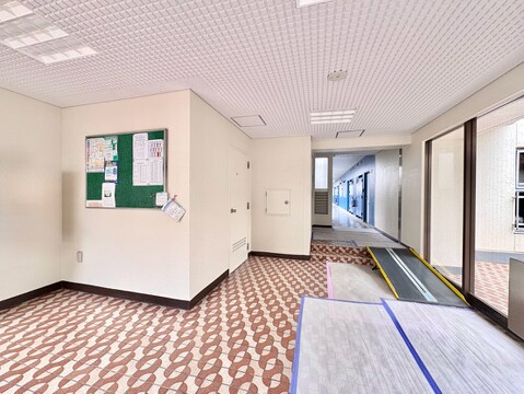 建物の共用スペース、掲示板と通路が見えるエントランスホール