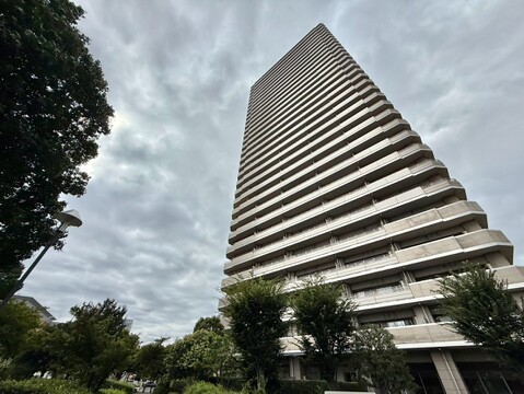 植栽に囲まれた高層マンションの外観