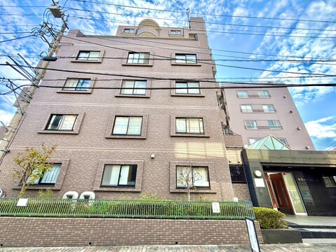 青空の下に建つ中層マンションの外観