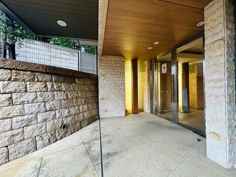 石貼りの壁と柱が特徴的な屋根付きアプローチ